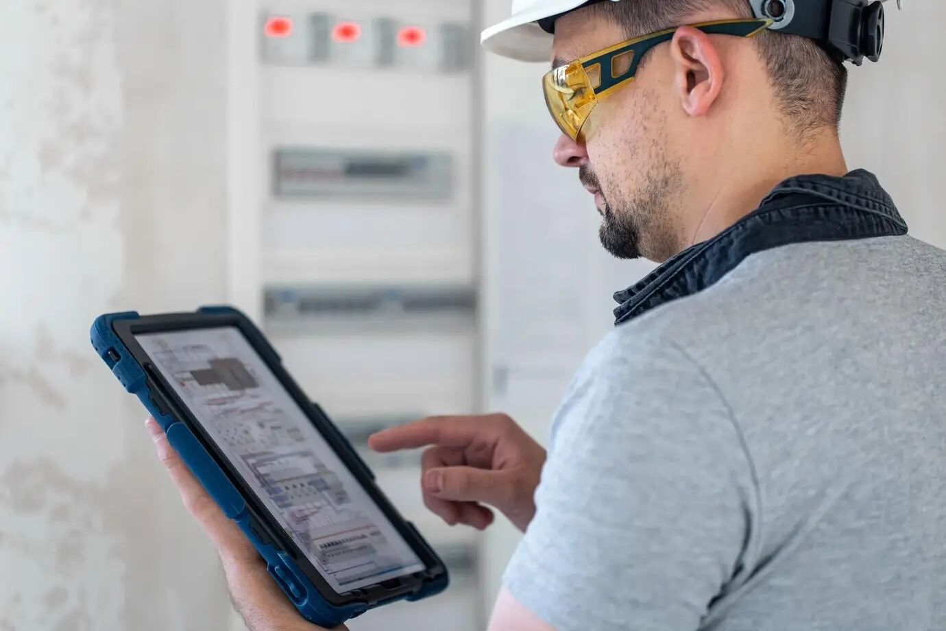 An electrical technician appears focused while working inside a fuse-equipped switchboard.