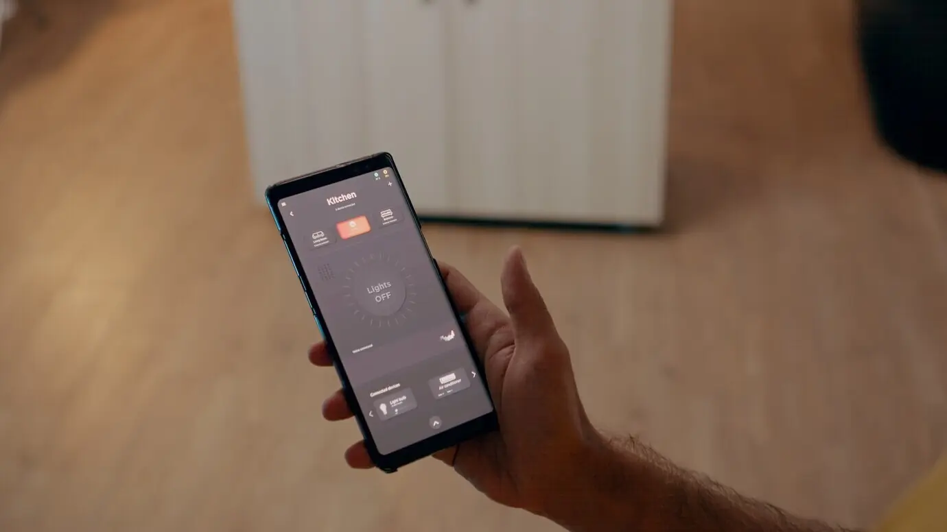 Close-up of a man using a voice-activated app to switch on bulbs in a smart home with an automation system.